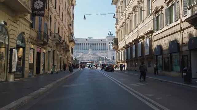 Lifestyle scene on people and traffic on street in Rome with background view of Venice square and Altar of the Fatherland with Vittorio Emmanuel II monument in Rome, Italy