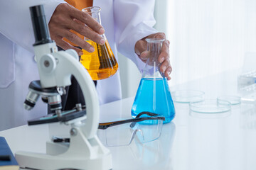 Scientist man holding test tube with color liquid. Laboratory assistant comparing samples in test...