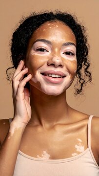 A woman with curly hair and a face mask smiles while touching her face