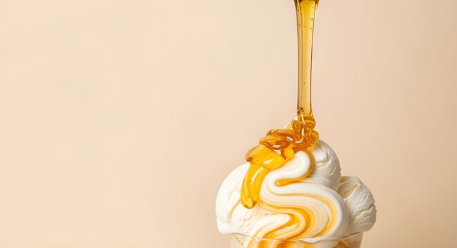 Honey drizzled over a swirly vanilla ice cream scoop on a beige background