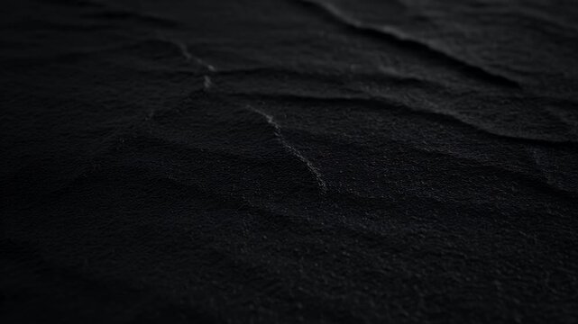 A dark, textured surface with subtle waves and folds, hinting at fabric or leather