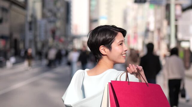 ショッピングバッグを持って銀座を歩く女性の後ろ姿のスローモーションショット