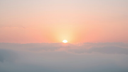 Obraz premium Soft pastel sunrise sky with sun rising above gentle cloud layer, peaceful warm glow