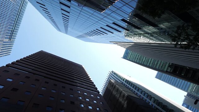 Low angle rotation of glass skyscrapers in modern Tokyo district.