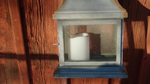 A candle in a cage hanging on a wall.