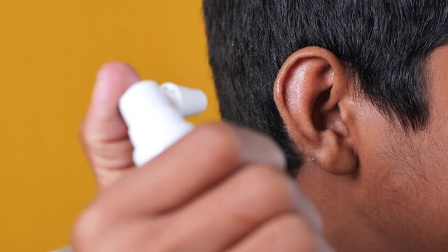 Person spraying ear drops into their ear for treatment or cleaning a close up shot