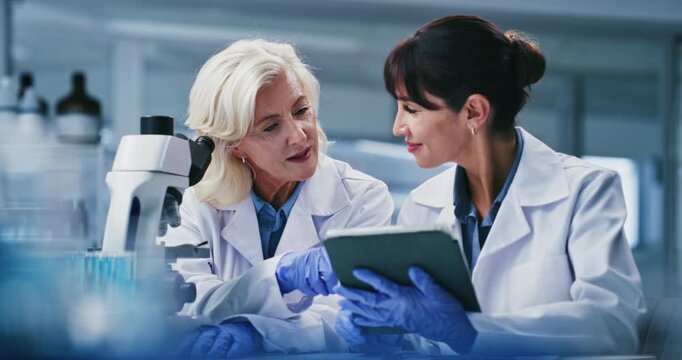 Microscope, talking and women on tablet in lab for teamwork, medical study and experiment results. Healthcare, mentor and scientists on tech for clinical trial, stem cell research and medicine review