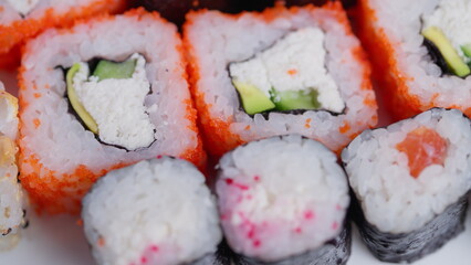 Colorful sushi closeup. Detailed shot of sushi ingredients. Fresh sushi with avocado and tobiko details. Vivid image showcasing assorted sushi with vibrant accompaniments © beholdereye