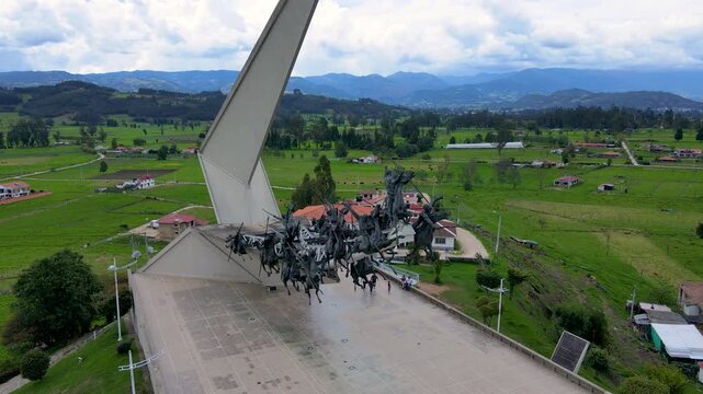 Aerial view of the Lanceros monument with green hills in the background and scattered houses, showcasing the grandeur of the sculpture.