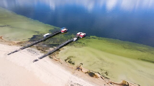 Aerial shot of Tota Lagoon showcasing wooden jetties and boats against clear blue waters.