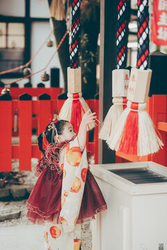 神社の鈴を鳴らす七五三の女の子