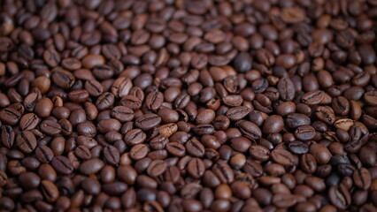 Obraz premium Closeup of glossy roasted coffee beans with warm lighting effects, Detailed image showcasing roasted coffee beans with warm glow and textured surface perfect for advertising