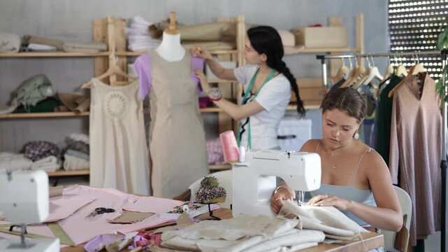 Team of dressmakers works on ordering clothes from a sewing workshop. Fashion designer checks the dress sample on a mannequin, and the seamstress works at the machine. High quality 4k footage