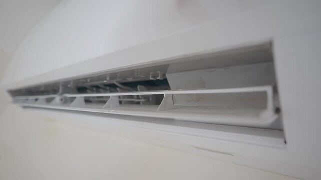 Air conditioner turns on, close up, warm air from air conditioner, split system on wall, air conditioning in room, cooling