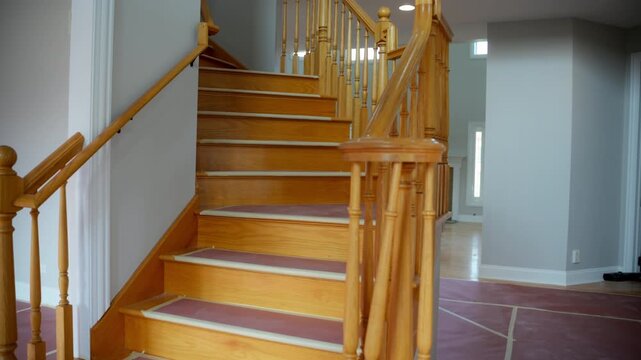 Interior shot of a residential staircase with wooden railing and carpeted steps. The stairs are covered with paper protection