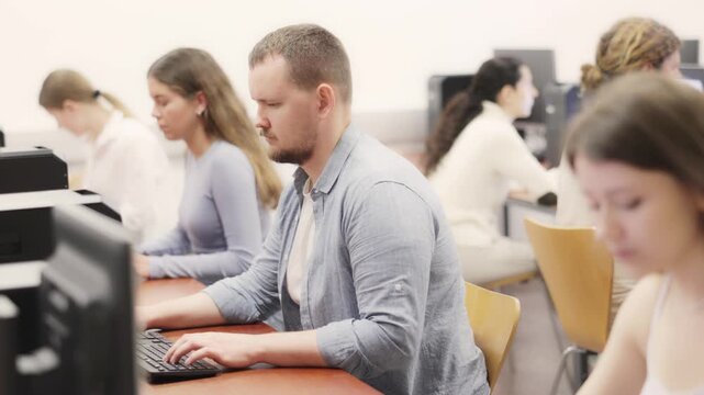 Adult man using computer for work in coworking space with team