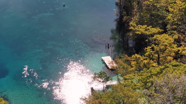 Turquoise spring pool and diving dock at Morrison Springs Florida, divers in water, aerial medium closeup, glistening reflections