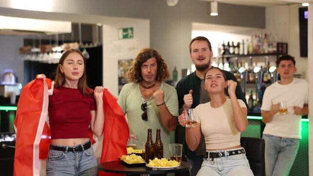 Excited canadian fans cheer for their team as they watch the match on TV in a beer bar. High quality 4k footage