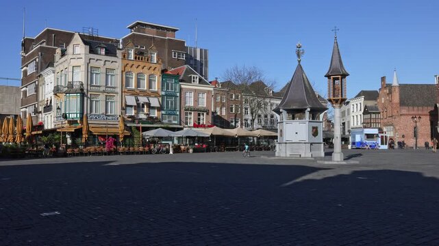 Historic market square in 's-Hertogenbosch featuring the ornate well and traditional gabled houses on a sunny day in the Netherlands.
