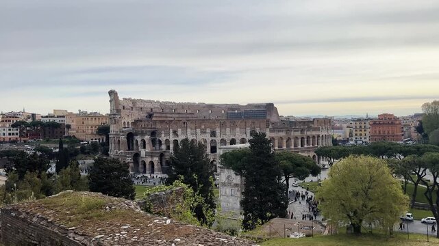 Panoramic view of Colosseum arena and Arch of Constantine in Rome, Italy  seen from park ruins in Roman forum during sunrise