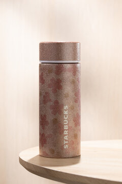 A pink glitter Starbucks limited edition stainless steel tumbler displayed on a wooden table, highlighting sparkling finish and collectible seasonal merchandise.
