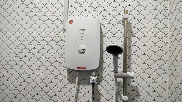 Malaysia Kuala Terengganu 3 March 2026: Shower and water heater in white bathroom. Small and compact bathroom, hot shower and shower head