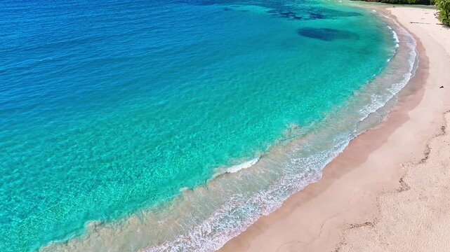 Close-up view of turquoise wave on tropical sandy beach of Indian Ocean. Sea waves on white sand. Waves crashing on a sandy beach. Summer seascape from the air. Changeable windy weather.
