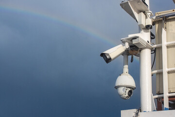 Outdoor Security Cameras on Ship Mast Under Dramatic Stormy Sky with Rainbow