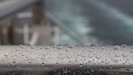 Raindrops on Metal Handrail of a Ship Deck with Blurred Sea Background