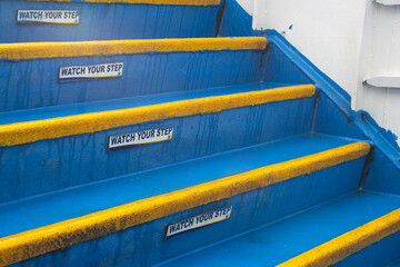 Warning Signs Watch Your Step on Blue Stairs with Yellow Safety Edging on a Ship
