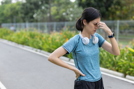 Fitness women feeling dizzy and exhausted after outdoor running workout in park. Health risk concept with fatigue, dehydration, overtraining, active lifestyle safety awareness.