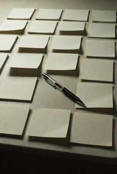 Multiple blank sticky notes on a desk with a pen representing planning and organization