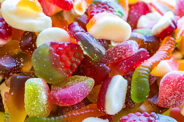 Close up macro texture of assorted gummy candies with sugar coating. Bright colorful jelly sweets background for candy branding, festive design and food industry concepts.