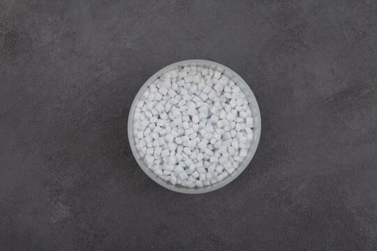 Virgin polyethylene terephthalate or Prime PET in plastic cup, top view. Granulated plastic polymer. Bottle grade PET-BG