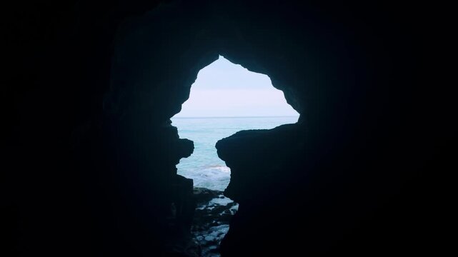 Silhouette of Africa-shaped cave opening at Caves of Hercules looking out to turquoise ocean.