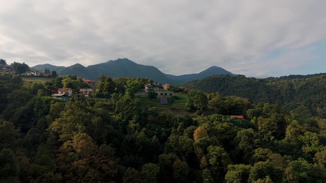 Aerial view of the village of Alzo surrounded by lush green forests on a hillside in the Piedmont region of northern Italy. Copy space