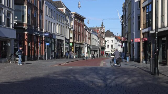 People walking through a pedestrian shopping street with historic architecture in the city center of 's-Hertogenbosch, Netherlands.