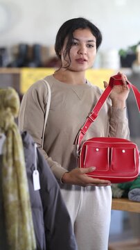 In sales area of store, Latin woman customer chooses handbag. Creating capsule wardrobe, branded clothing at affordable prices. Modern urban fashion, casual practical clothes