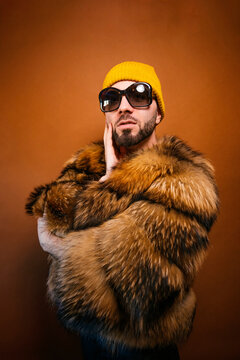 Fashionable man in fur coat and sunglasses posing