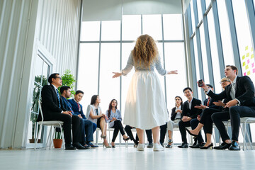 Rear view of female business coach standing confidently at center of modern glass office during...