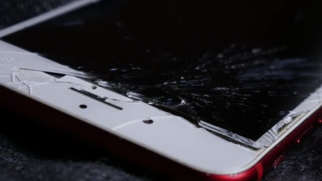 Broken cracked smartphone screen Phone red on dark fabric background, shattered glass display damage concept