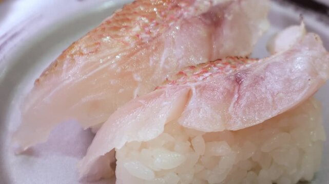 Fresh white fish nigiri sushi with skin-on snapper or sea bream on ceramic plate, Japanese traditional cuisine