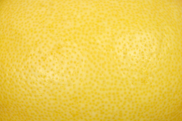 A detailed macro shot captures the textured yellow skin of a fresh lemon showing small pores and subtle surface variations. © nahhan