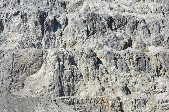 A close up view of a steep stone quarry face showing intricate rocky layers and rough textures of excavated limestone under bright daylight