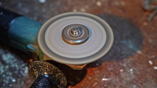 Closeup view of angle grinder disc rotating during metal cutting process. Power tool operating with abrasive wheel in workshop environment.