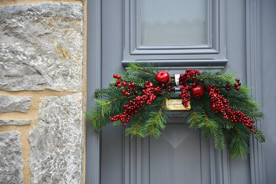 Scenic view of a Neoclassical house grey entrance door against a stone wall, decorated with a X-mas mistletoe arrangement in Leonidio, Arcadia Peloponnese, Greece.