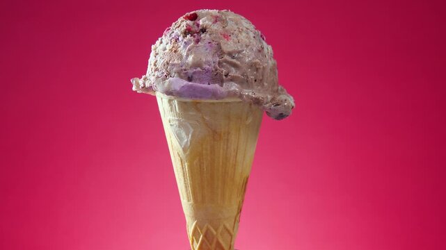 Ice cream in a waffle cone slowly rotates around its axis against a bright background