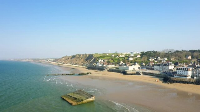 Aerial view of the sandy beach and coastal village of Arromanches les Bains in Normandy, France on a clear day.