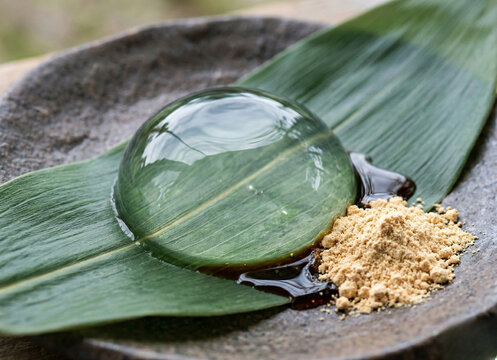 Transparent Mizu Shingen Mochi raindrop cake on a bamboo leaf with syrup