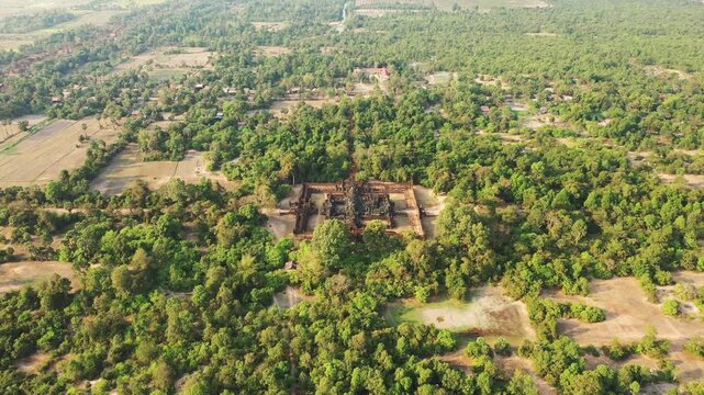 Drone shot of the ancient Banteay Samre temple surrounded by lush green forest and rural landscape in Cambodia.